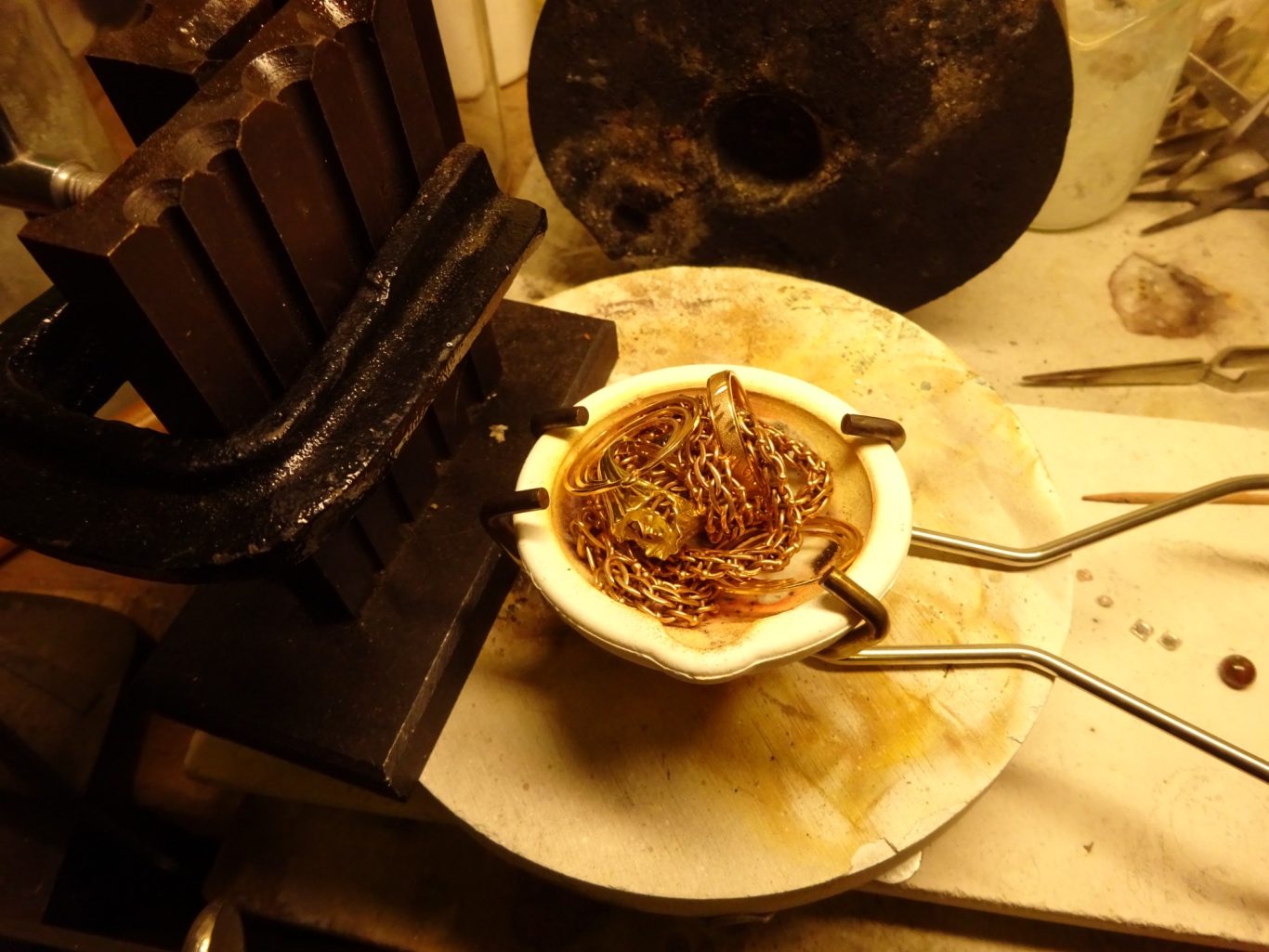 Händisch gefertigte Kaffeetasse auf einer Werkbank mit einer Presse daneben.